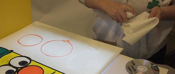 Kris cleaning an art board with circle draw with a Zig Posteman Marker