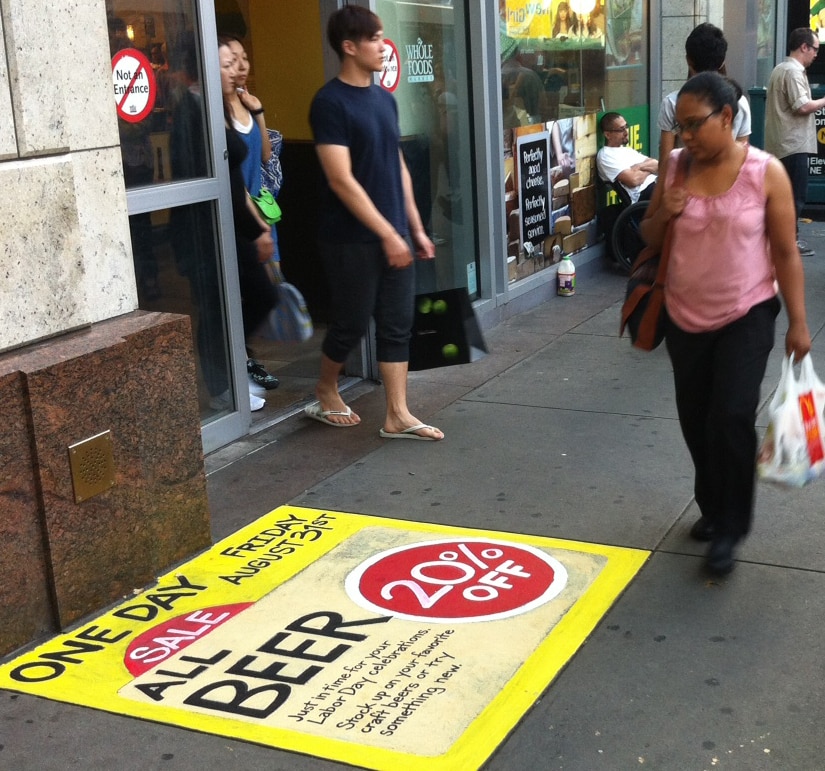 Bright Yellow Beer ad showing 20% off on the sidewalk done with Zig Posterman Sidewalk Paint Markers