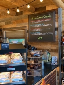 Framed chalkboard sign with bright liquid chalk paint lettering hangs at the counter of a bistro. The sign sparks the desire for Steed to begin a new chalkboard business venture.